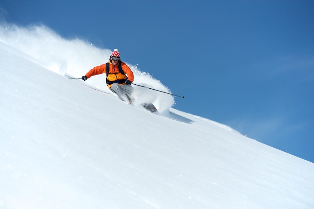 Esquiador de freeride bajando por nieve virgen